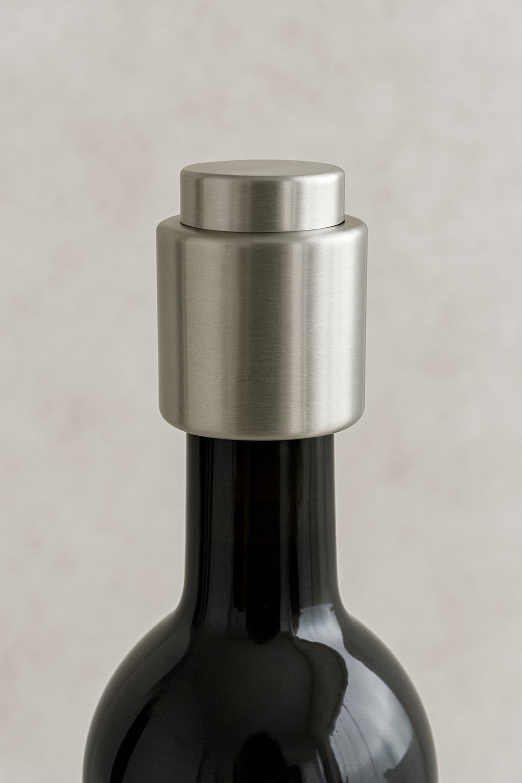 A close-up image of a silver stainless steel wine bottle stopper placed on top of a wine bottle, illustrating the product's use.